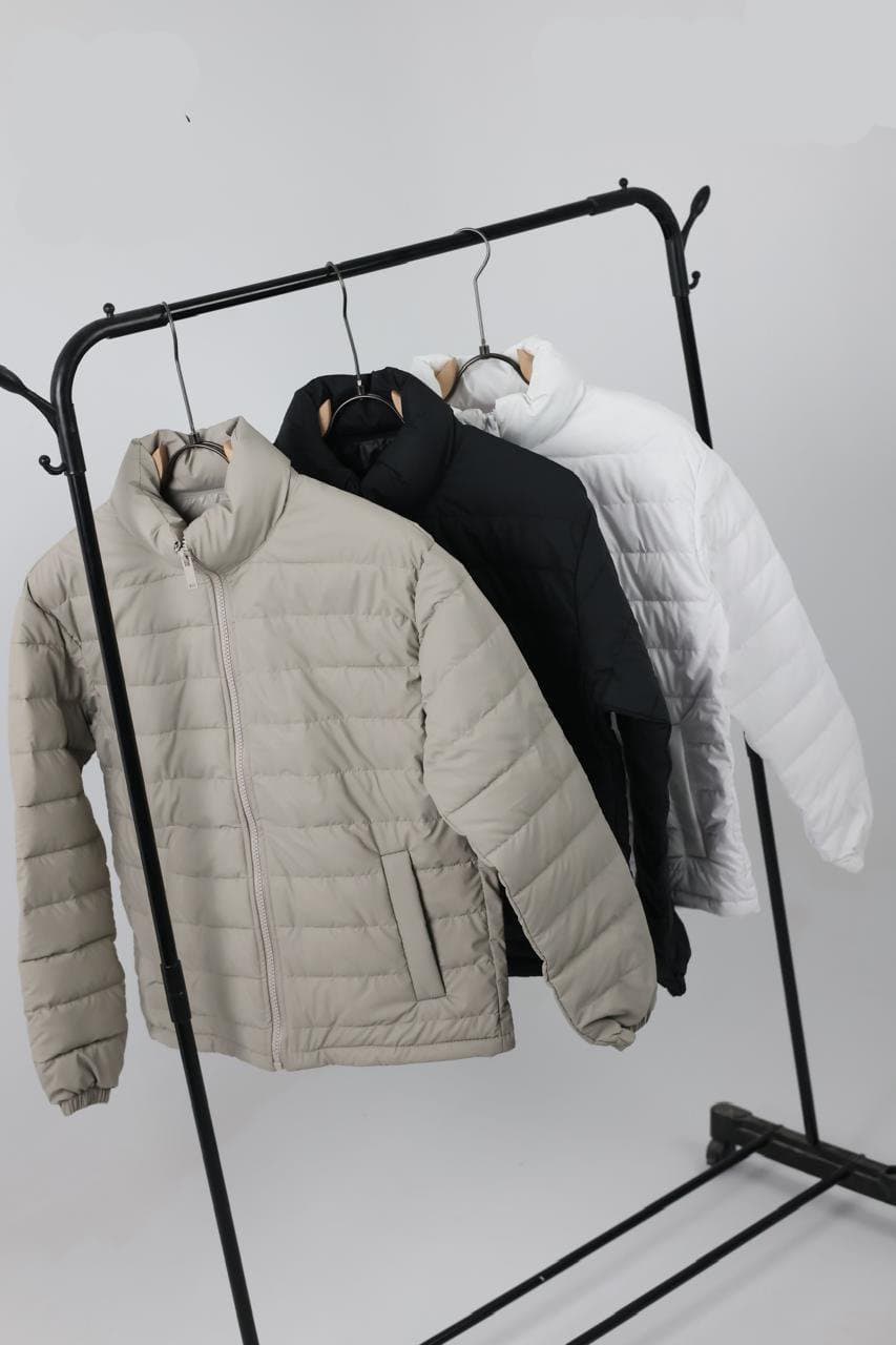 Lightweight quilted puffer jackets on a rail in stone, black and white colourways
