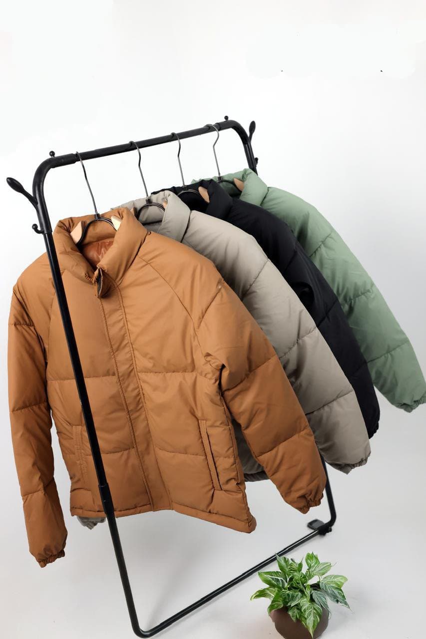 Quilted puffer jackets on a rail in caramel, taupe, black and sage colourways