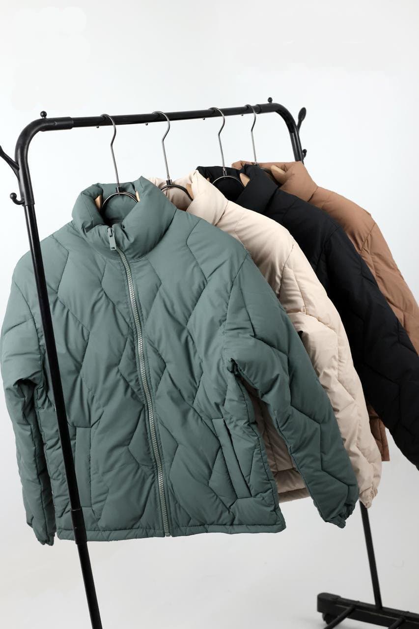 Chevron-quilted puffer jackets on a garment rail in sage, cream, black and tan colourways